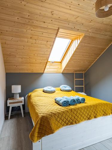 a bedroom with a yellow bed with a wooden ceiling at Pod Lasem Apartamenty in Łukęcin