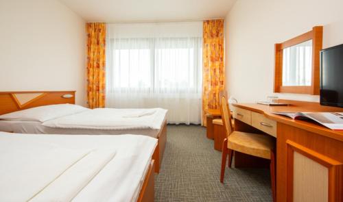 a hotel room with two beds and a desk at Hotel SOREA TITRIS in Tatranská Lomnica