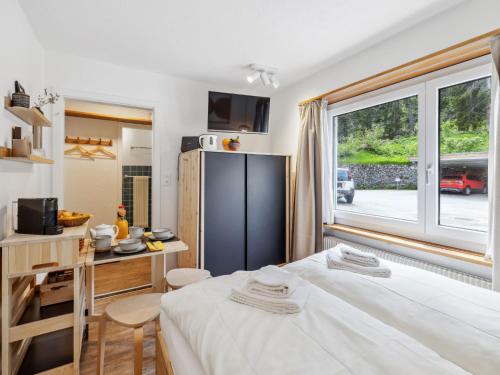 a bedroom with a bed and a kitchen with a window at Apartment Promenade - Utoring-19 by Interhome in Arosa