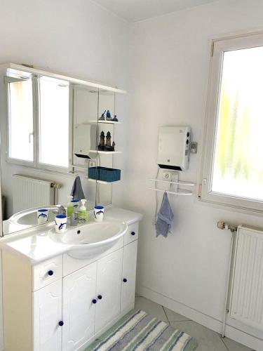une salle de bain blanche avec un lavabo et un miroir dans l'établissement Grace, à Douzy