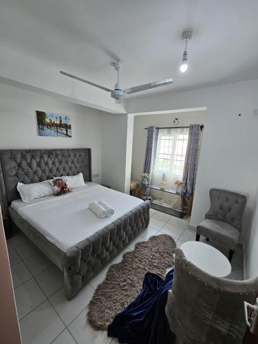 a bedroom with a large bed and a chair at SuCasa Homes in Mombasa