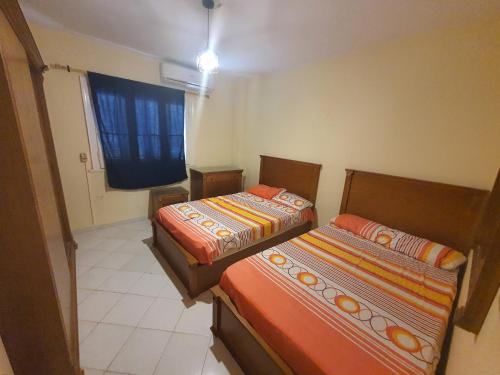 zwei Betten in einem kleinen Zimmer mit Fenster in der Unterkunft Chalet Marina Flowers Resort in El-Alamein