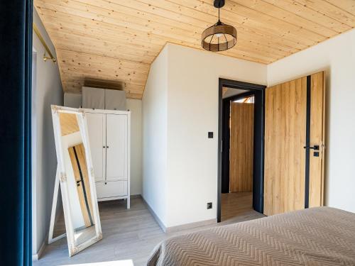 a bedroom with a bed and a wooden ceiling at Pod Lasem Apartamenty in Łukęcin