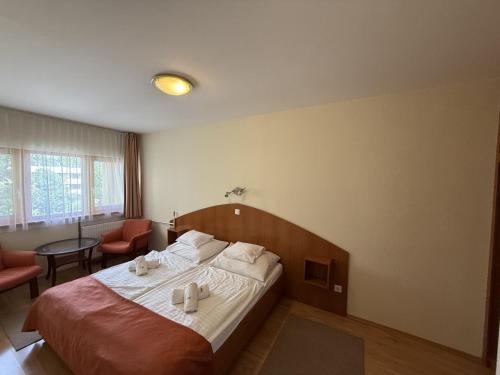 a bedroom with a bed with two white towels on it at Apartman Hotel in Bük