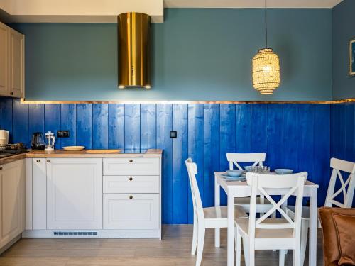 a kitchen with blue walls and a table and chairs at Pod Lasem Apartamenty in Łukęcin
