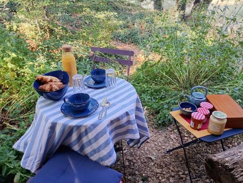 une table avec une nappe bleue et blanche et une bouteille de jus dans l'établissement La Bergerie en Provence, à Puimichel