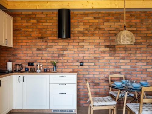 a kitchen with a brick wall and a table with chairs at Pod Lasem Apartamenty in Łukęcin