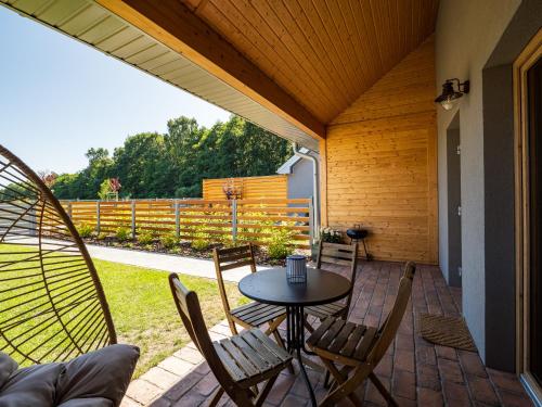 a patio with a table and chairs and a fence at Pod Lasem Apartamenty in Łukęcin
