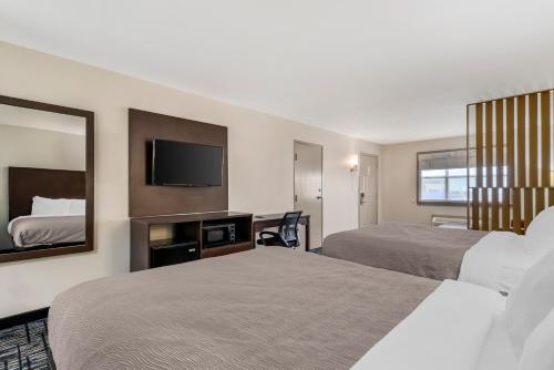 a hotel room with two beds and a flat screen tv at Quality Inn & Suites I-10 near Fiesta Texas in San Antonio