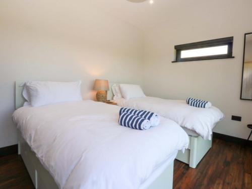 two beds in a room with white sheets and a window at Y Cwt in Moelfre