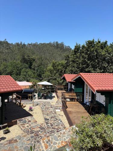 a resort with a deck and a patio with tables and benches at Mimosa Village - Turismo de Natureza in Mortágua