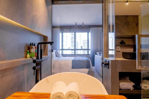 a bathroom with a bath tub and a bedroom at Radisson Rio de Janeiro Barra in Rio de Janeiro