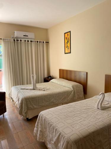 a hotel room with two beds and a window at Hotel Fazenda Tucano in Capim Branco