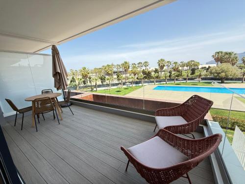 a balcony with chairs and a table and a pool at Oceans Oliva in Oliva