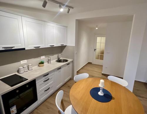 a kitchen with a wooden table and white cabinets at Una Sky Apartment in Prijevor