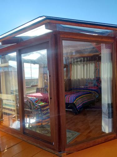 a room with glass doors with a bed in it at Uros Titicaca coila lodge in Puno