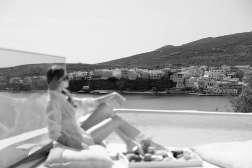 a woman sitting on the edge of a balcony overlooking a city at Golden Vista, Beachfront Suites by Explore Andros in Andros