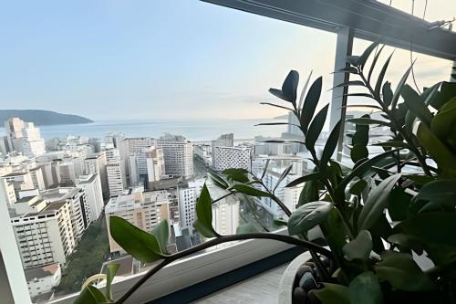 a view of a city from a window with a plant at Alto padrão com vista panorâmica in Santos