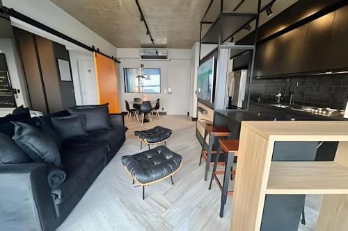 a living room with a black couch and a kitchen at Alto padrão com vista panorâmica in Santos