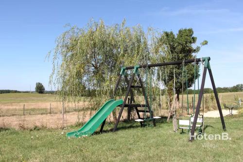a swing set in a field with a tree at Rouge Tanin Cottage Private Spa Nature & Authentic Charm on a Dordogne in Blanc