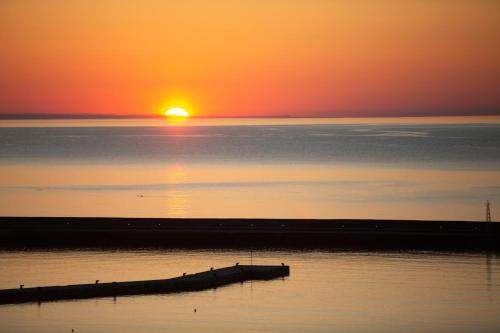 a sunset over a body of water with a pier at Golden Vista, Beachfront Suites by Explore Andros in Andros