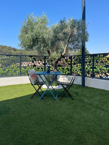 une table et deux chaises assises sur l'herbe dans l'établissement Le Castellet Maison de vacances, au Castellet