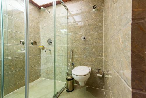 a bathroom with a toilet and a glass shower at Treebo Globe International Near Kalighat Mandir in Kolkata