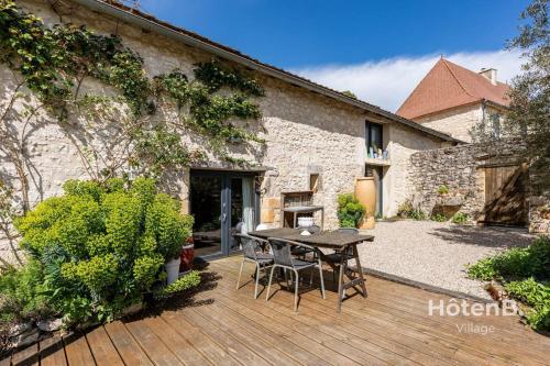 une terrasse en bois avec une table en face d'un bâtiment dans l'établissement Douce Campagne Cottage Private Spa, à Blanc