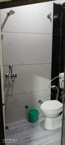 a bathroom with a toilet and a green bucket at Sankalp Yatri Nivas AC dormitory in Gwalior