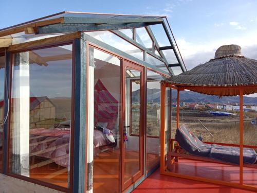 a glass house with an umbrella and a couch at Uros Titicaca coila lodge in Puno