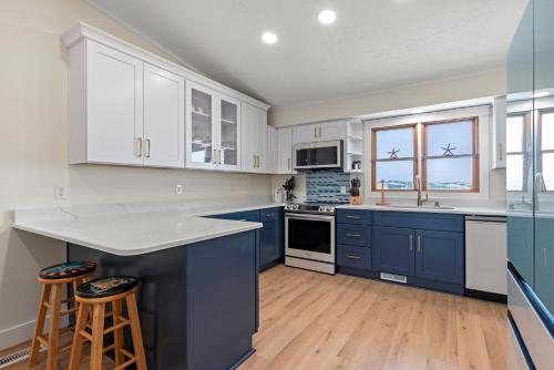 cocina con armarios azules y blancos y suelo de madera en The Blue Pelican, en Kitty Hawk