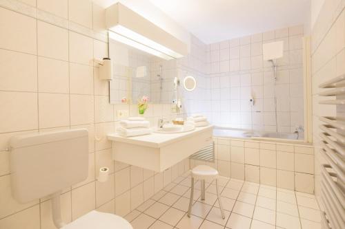 a white bathroom with a sink and a toilet at Parkhotel Emstaler Höhe in Bad Emstal