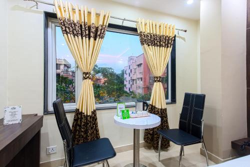 a room with a table and chairs and a window at Treebo Globe International Near Kalighat Mandir in Kolkata