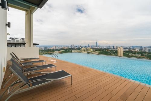 a pool on the roof of a building with chairs at Ooak Residence in Mont Kiara, Kuala Lumpur in Kuala Lumpur