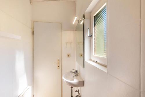a white bathroom with a sink and a mirror at db staycation ferienpark in Niedenstein