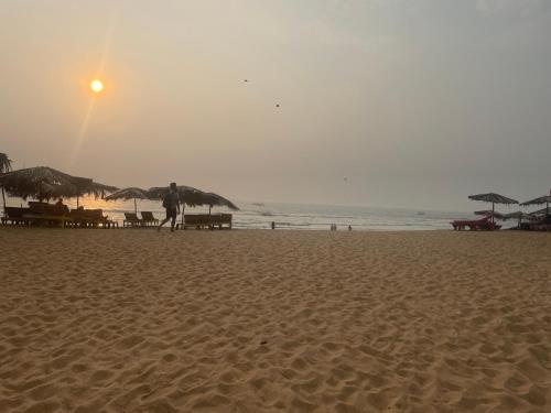 a person walking on a sandy beach with umbrellas at Richita resort in Calangute