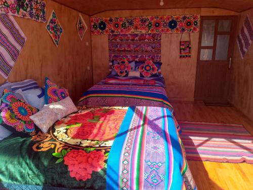 a bed with a colorful comforter in a room at Uros Titicaca coila lodge in Puno