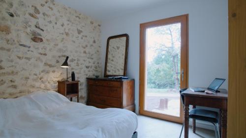Un dormitorio con una cama, un escritorio y un espejo. en Théveny, Le Couchant, en Saint-Astier