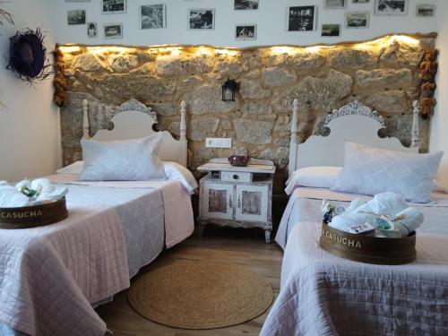 a bedroom with two beds and a stone wall at La Casucha junto al mar in Vilagarcia de Arousa