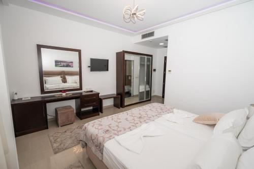 a bedroom with a bed and a desk and a mirror at The One Boutique Hotel in Muçaj