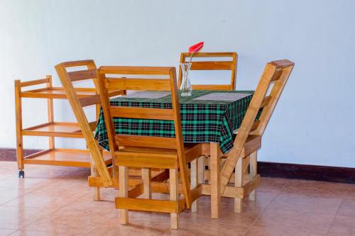 a table with three chairs and a green table cloth at Stay Inn Back Packers in Arusha