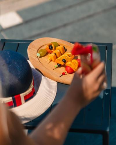 a person holding up a plate of fruit with a hat at The One Boutique Hotel in Muçaj