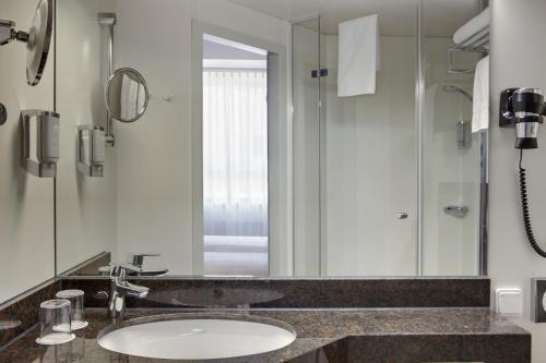 uma casa de banho com um lavatório e um espelho em Rugs Hotel Augsburg City em Augsburg