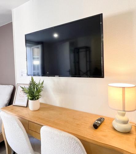 une télévision sur un mur avec télécommande sur un bureau dans l'établissement Studio B4 - Centre-Ville Meaux - Proche Disneyland, à Meaux