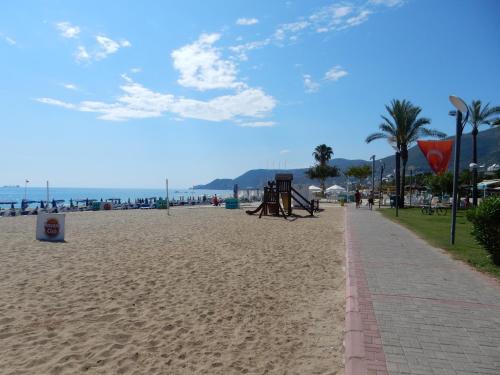 a sandy beach with palm trees and a sidewalk at Aysev Hotel in Alanya