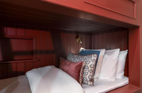a bed with white pillows on a red wall at Munro Guest House in Stirling