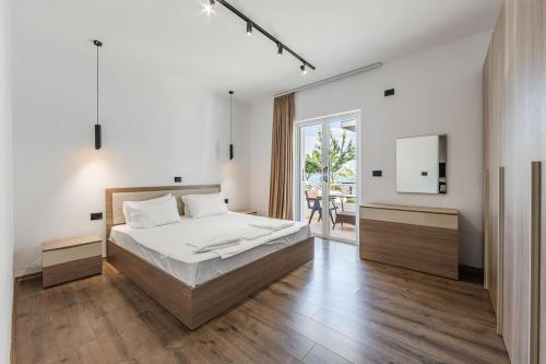 a white bedroom with a bed and a sliding glass door at Saranda Beach Living - 1BR Apartment in Sarandë