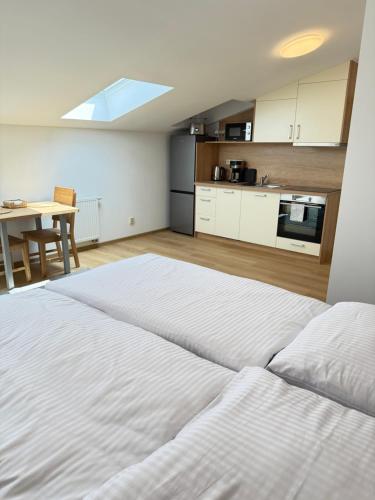 a bedroom with a large white bed and a kitchen at Riverside Apartment Praha in Prague