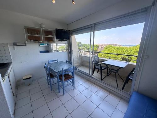 une cuisine et une salle à manger avec une table et un balcon dans l'établissement Beau Studio direct plage, au Grau-du-Roi