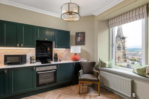a kitchen with green cabinets and a chair and a window at Munro Guest House in Stirling